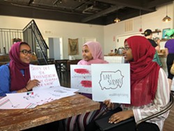Rana Sulieman (left), Hiba Ahmed, and Olaa Mohamed hold signs they've made for Saturday's protest. - PHOTO BY EFUA AGYARE-KUMI