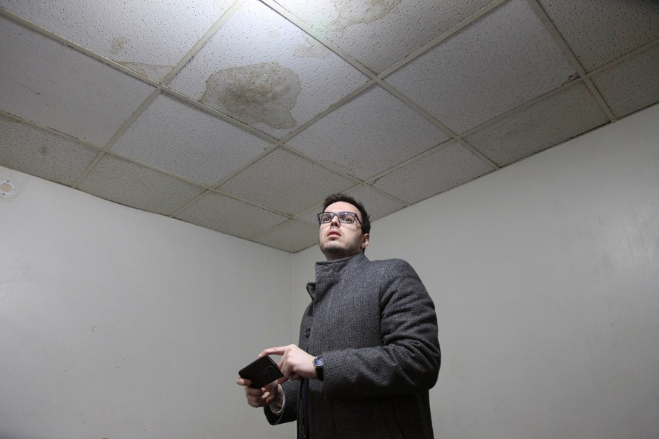 Mike Furlano, an attorney with the Legal Aid Society of Rochester, photographs water stains and damaged ceiling tiles in one room of Linda Barger's apartment. - PHOTO BY MAX SCHULTE