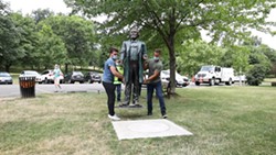 John Boedicker, left, and Charles Milks carry a Frederick Douglass statute made by sculptor Olivia Kim to its base at Kelsey's Landing in Maplewood Park. - PHOTO BY MAX SCHULTE