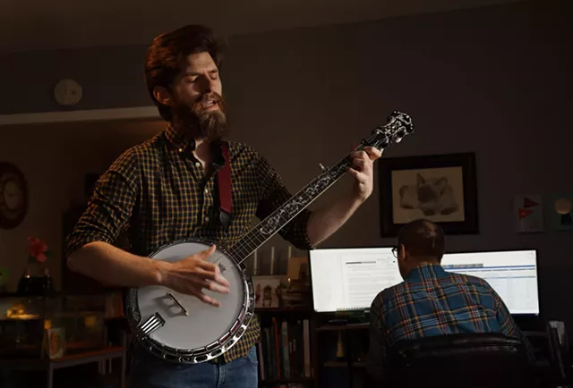 Philip Detrick plays the banjo as his brother works from home. Detrick moved into his brother's Webster home in September and hopes to get his own apartment soon. - PHOTO BY MAX SCHULTE