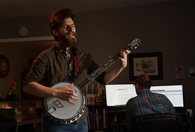 Philip Detrick plays the banjo as his brother works from home. Detrick moved into his brother's Webster home in September and hopes to get his own apartment soon. - PHOTO BY MAX SCHULTE