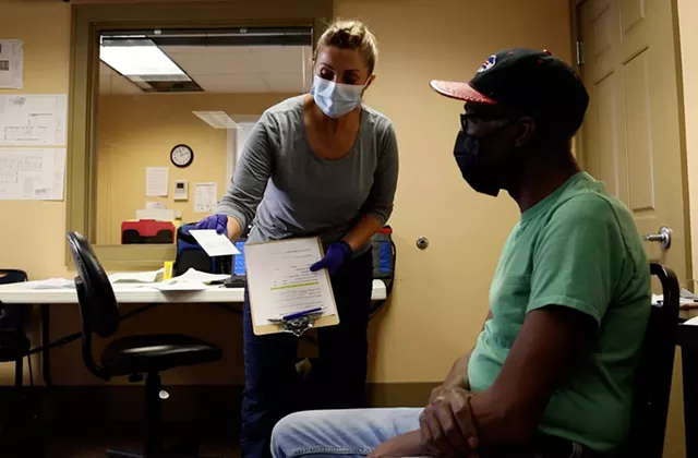 VA Finger Lakes Healthcare System nurse, Lisa Lehning, shows C.L. Scribling the CDC vaccination card he'll receive after his shot of the Johnson & Johnson COVID-19 vaccine. - PHOTO BY MAX SCHULTE / WXXI NEWS