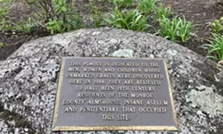 A plaque on a rock in the center of the garden marks the place where hundreds of people were buried, nameless and en masse. - PHOTO BY NOELLE E. C. EVANS