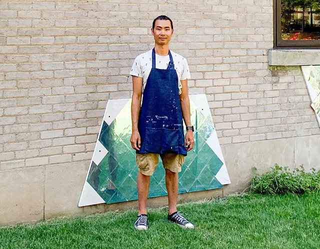 Thai artist Ong Siraphisut installing his mural "BREATHE," which is made of mirrored stickers that reflect the park, city buildings, and viewer. - PHOTO PROVIDED