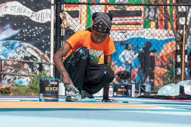 Paris Cockrell, part of the 2021 Peculiar Asphalt team, paints this year's final basketball court at the Roxie Ann Sinkler R-Center. - PHOTO BY RYAN WILLIAMSON