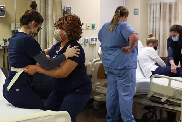 Cait Elsadek and Tessy Michael practice how to move patients in and out of a wheel chair from a bed at the hands-on skills lab at the University of Rochester School of Nursing. - PHOTO BY MAX SCHULTE / WXXI NEWS