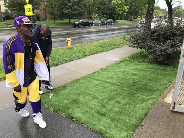 Anthony (Tony) Lovett, left, on his putting green outside the Lake Avenue Mini Market, where he worked as a clerk. In the background, a customer hits the links. - PHOTO BY DAVID ANDREATTA