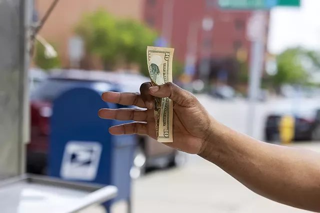 A customer of George Haddad offers a $10 bill to pay for lunch. Ten dollars can go a long way at Haddad's stand, which has the lowest prices of the downtown vendors. - PHOTO BY LAUREN PETRACCA