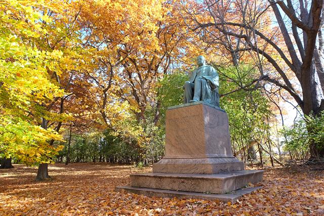A statue of Edward Mott Moore, who championed the development of a parks system in Rochester, stands at the edge of Genesee Valley Park, in front of a wooded area that the University of Rochester owns. - PHOTO BY JEREMY MOULE