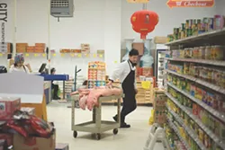 An employee moves pigs to the meat counter in Asia Food Market in Henrietta. - PHOTO BY THOMAS DOOLEY