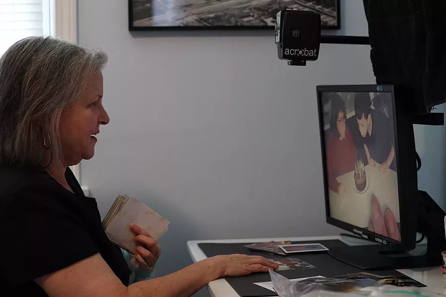 Patty Starr uses a magnifier to edit and digitize family photos — a project that helps her cope with being at home for days at a time. - PHOTO CREDIT MAX SCHULTE