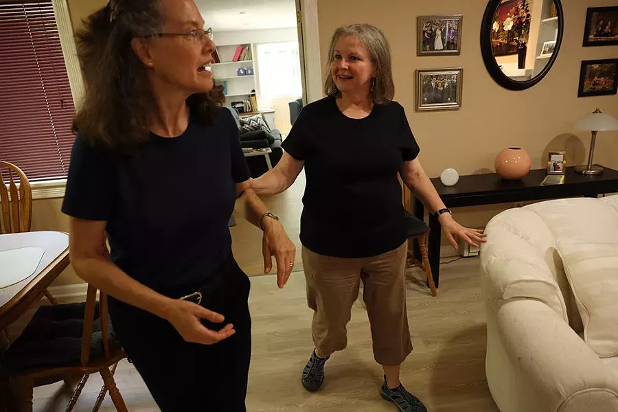 Patty Starr, who is deafblind, holds the arm of interpreter Elisa Mlynar as they walk in Starr's home. - PHOTO CREDIT MAX SCHULTE