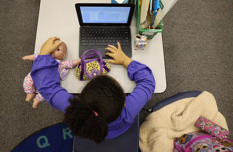 Alianna Lee and her doll Sophie log into her next class after finishing lunch. Kids eat at their desks and then teacher's aides disinfect the work areas. - PHOTO BY MAX SCHULTE / WXXI NEWS