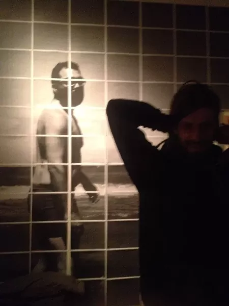 Musician and artist Joel Dow in front of John Lake's photo installation at Axom. - PHOTO BY REBECCA RAFFERTY