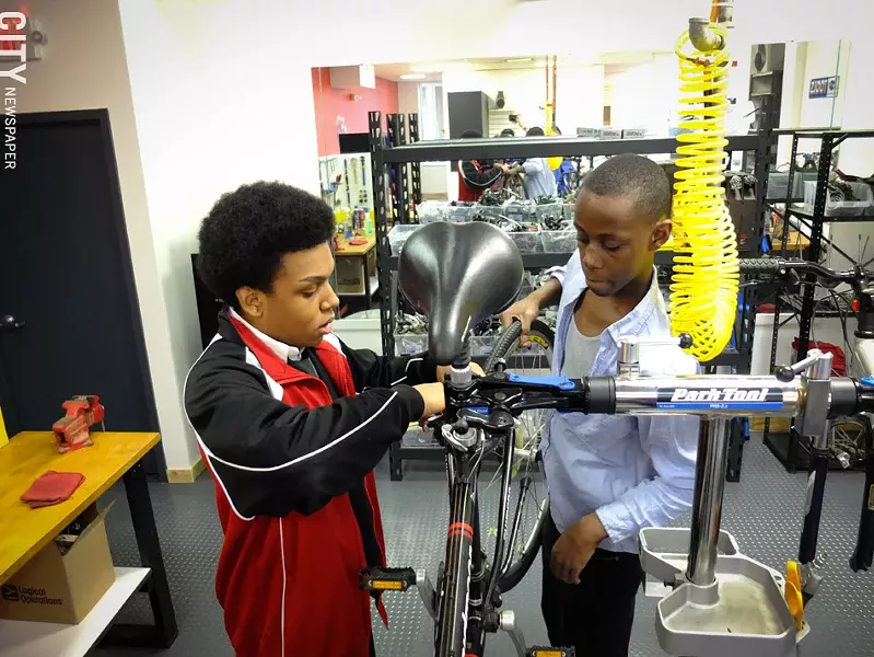 David Gayle,16, and Shandan Jones,17, both of Vertus High School, change a wheel at Dream Bikes on University Avenue. - PHOTO BY KEVIN FULLER