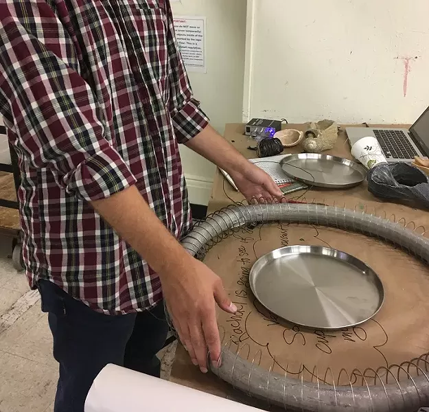 A "Rainforest IV" collaborator explains a how an instrument is made from scrap metal. - PHOTO BY REBECCA RAFFERTY