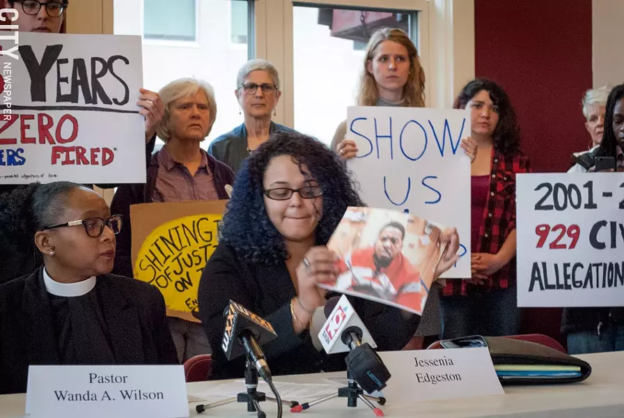 Jessenia Edgeston holds up a picture of her husband taken after his encounter with police. - PHOTO BY RYAN WILLIAMSON
