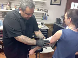 Orlando-based tattoo artist Rick Rosas transfers an image on a client at Los Muertos Tattoo Company in the Medical Center. Rosas was left without a place to work when the final day of the Texas Tattoo Jam was cancelled after promoter Renee "Red" Neilson failed to pay the San Antonio Event Center for renting the venue. Los Muertos owner Lupe Diaz Jr. opened his shop to Rosas to help him recoup some of his losses. - KIKO MARTINEZ