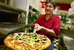 Owner and manager Terry Basore takes a piping hot medium ""Mama Mia"" pizza out of the oven at Pizza Italia. The Mama Mia features pepperoni, Italian sausage, beef, black olives, mushrooms, onions, green peppers, and jalapeÒos.
