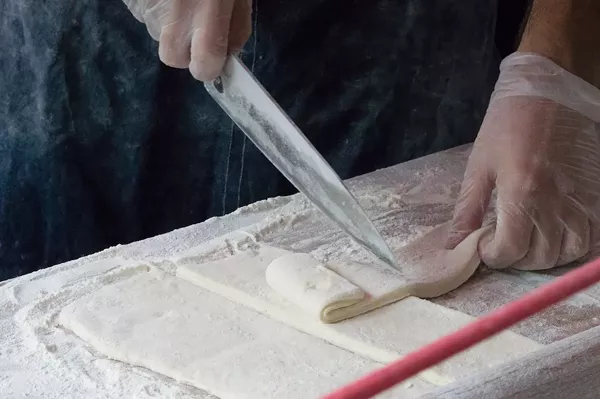 Grimes rolls out the beignet dough to a large rectangle, before cutting. - LEA THOMPSON