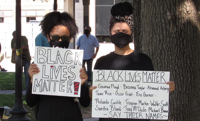 Two protesters hold up signs at a San Antonio march against police brutality. - SANFORD NOWLIN