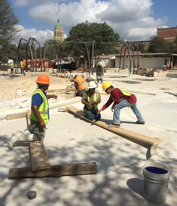 Oscar Alvarado works with construction crew members to create an undulating ripple effect in concrete. - BRYAN RINDFUSS
