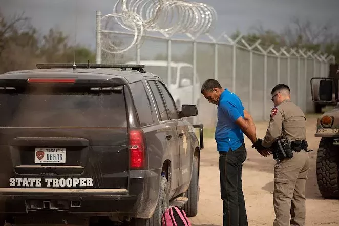 A Texas Department of Public Safety trooper arrests Nerio, a Venezuelan migrant, on private riverside property in Del Rio, just beyond a newly installed fence paid for by the state. Credit: Miguel Gutierrez Jr./The Texas Tribune - TEXAS TRIBUNE / MIGUEL GUTIERREZ JR.