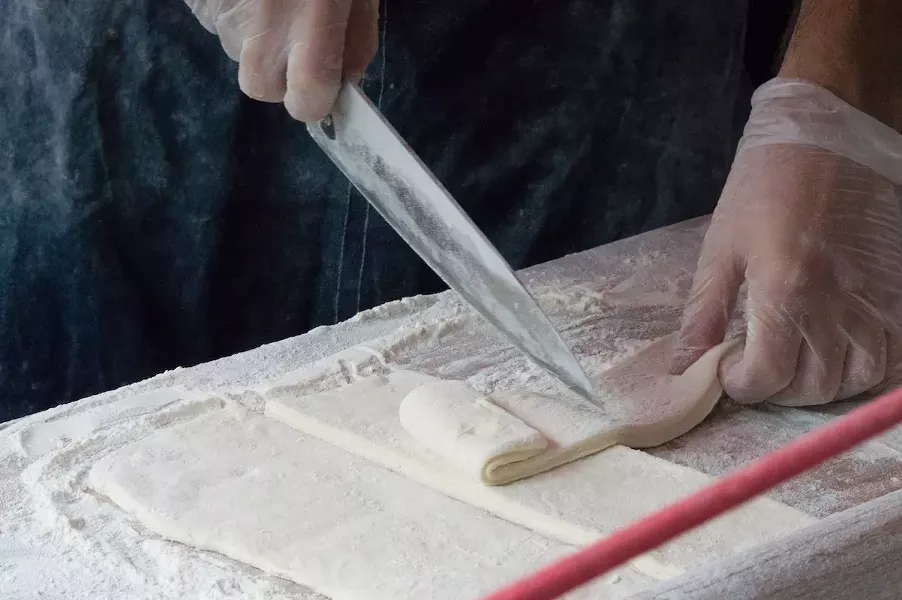 Grimes rolls out the beignet dough to a large rectangle, before cutting. - LEA THOMPSON