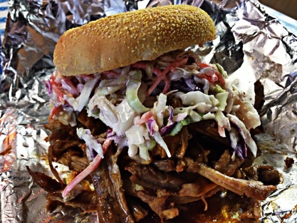 A pulled pork sandwich topped with a pile of slaw. - JEFFREY DAVID