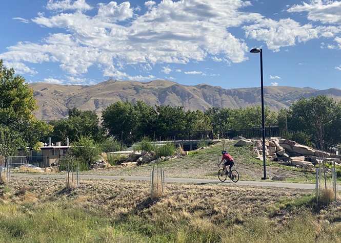 A cyclist passes a recently-constructed stormwater collection site in Rose Park along the Jordan River Parkway on Thursday, September 1, 2022. - BENJAMIN WOOD