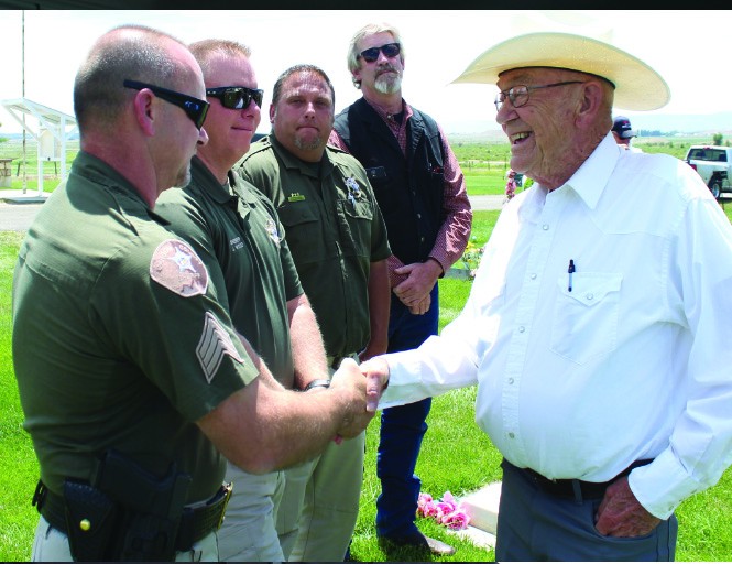 Carbon County Sheriff's Detective David Brewer shakes hands with Duane Jones, Loretta’s brother, at the Elmo Cemetery on the day her body was reinterred. On the night of the crime, Duane and his father were across the street from the house in which the murder took place. Also in the photo are Carbon County Sheriff Jeff Wood, Chief Deputy Cletis Steele and Detective Wally Hendricks.