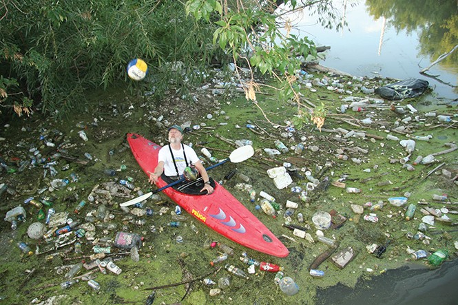 Ray Wheeler, surrounded by garbage, floats in his kayak down the Jordan River. - AMY O'CONNOR