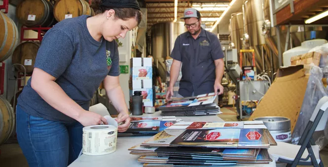 15. Alisha Telles and Brandon Smith assemble and label boxes.