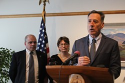 Chief of health care reform Lawrence Miller and director of health care reform Robin Lunge watch as Gov. Peter Shumlin speaks at a news conference Monday. - PAUL HEINTZ