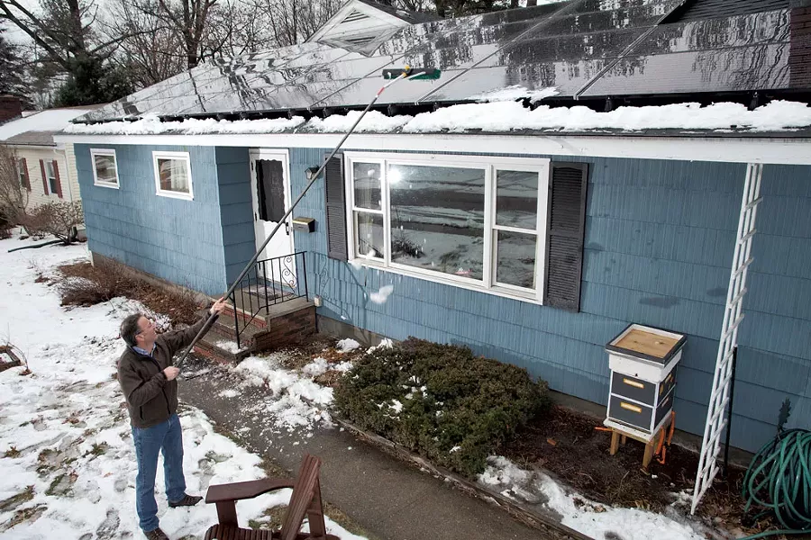 Nik Ponzio cleans the solar panels on his retrofitted home - MATTHEW THORSEN