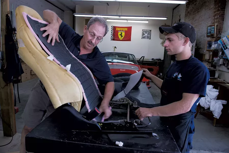 Ortuno and Raymond upholster a car seat.