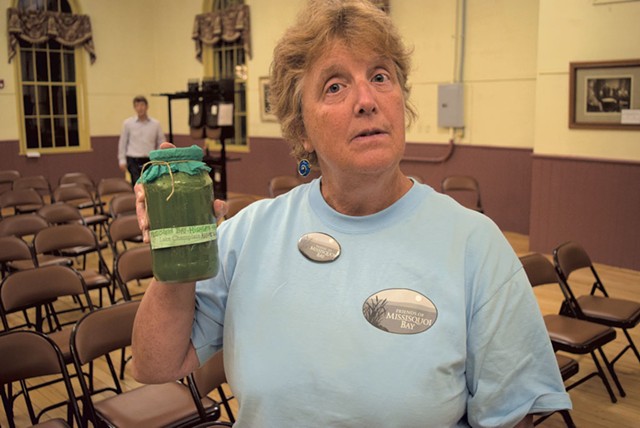 Colleen Curran holding a sample of algae-filled water - TERRI HALLENBECK