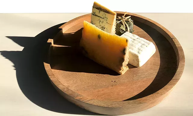Piedmont and Lombardy cheese board at Dedalus Wine Shop: Robiola Tre Latti Fico (in leaf), Bergamino di Bufala (white square), Castelmagno d'Alpeggio (golden), Blu Imperiale (blue) - SUZANNE M. PODHAIZER