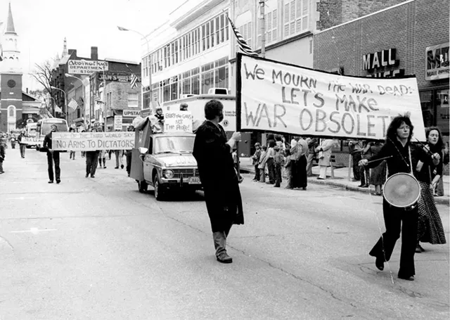 Robin Lloyd banging a drum on Burlington's Church Street with the Peace & Justice Center's Wendy Coe in the background, circa 1980 - COURTESY OF GREG GUMA