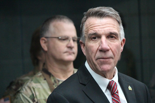 Maj. Gen. Steven Cray (background) looks on as Gov. Phil Scott addresses the media - PAUL HEINTZ