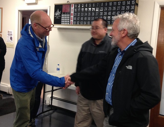 Winooski Superintendent of Schools Sean McMannon (left) shakes hands with school board chair Mike Decarreau (right) as school board member Alex Yin looks on. - MOLLY WALSH