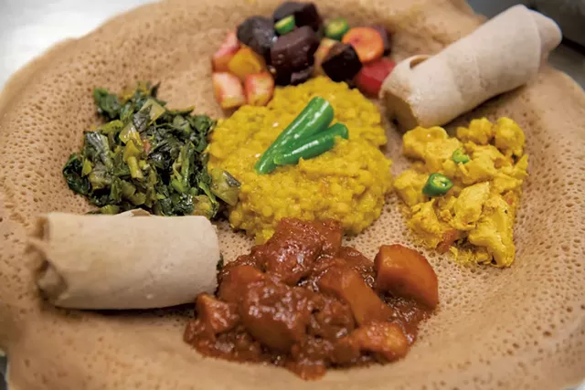 Ethiopian and Eritrean lentils, carrots, beets and potatoes, collard greens, curried chicken, and spicy potatoes, served on injera bread, for a takeout dinner at the O'Brien Community Center - DARIA BISHOP
