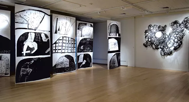 Gallery view, featuring "Black Holm" banner screenprints by Fraser Taylor and "Hive" aluminum and wire sculpture by Jodi Colella
