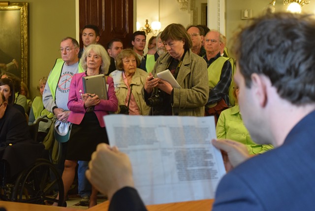 Sen. Tim Ashe (D/P-Chittenden) reads over details of the revised bill as onlookers crowd a Statehouse meeting room. - TERRI HALLENBECK