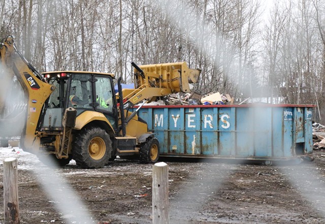 A loader piles debris into a dumpster - COURTNEY LAMDIN ©️ SEVEN DAYS