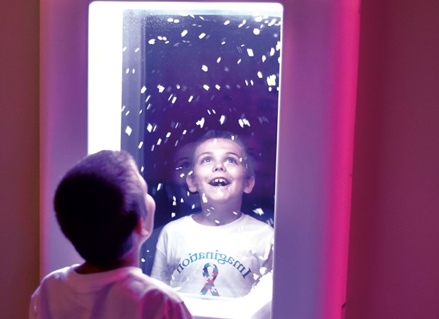 Ethan Slayton, 8, watching virtual - snowflakes at an interactive wall panel - JEB WALLACE-BRODEUR