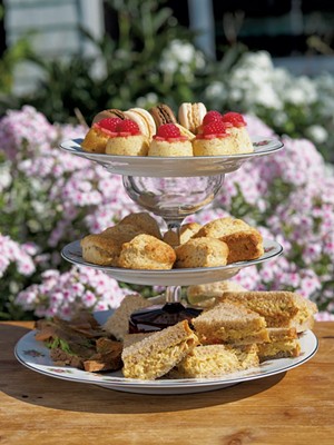 A tiered tray holding cookies, scones and finger sandwiches - ANDY BRUMBAUGH