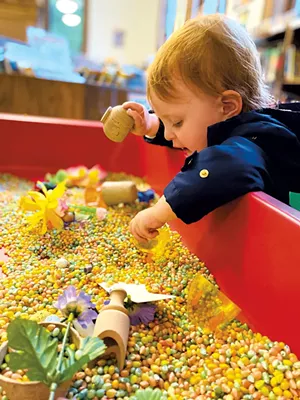 Exploring a sensory bin at Fletcher Free Library - JULIE GARWOOD