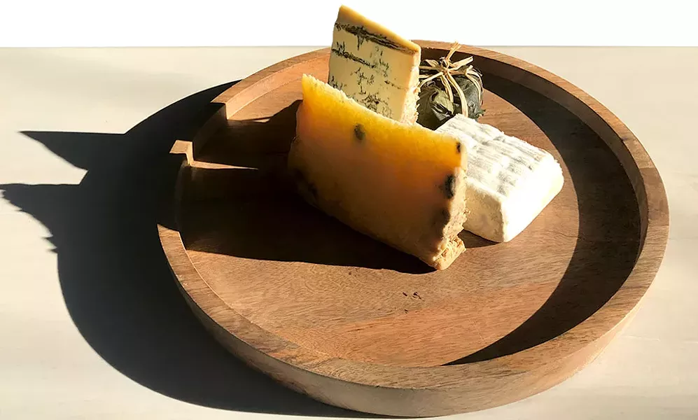 Piedmont and Lombardy cheese board at Dedalus Wine Shop: Robiola Tre Latti Fico (in leaf), Bergamino di Bufala (white square), Castelmagno d'Alpeggio (golden), Blu Imperiale (blue) - SUZANNE M. PODHAIZER