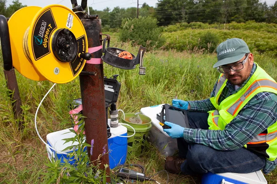 Aaron Sutton tests a well outside the Air National Guard base in Burlington last week. Sutton works for Parsons Corp., the environmental firm performing a range of tests to see if contamination on the base has migrated toward the Winooski River. - KEVIN MCCALLUM